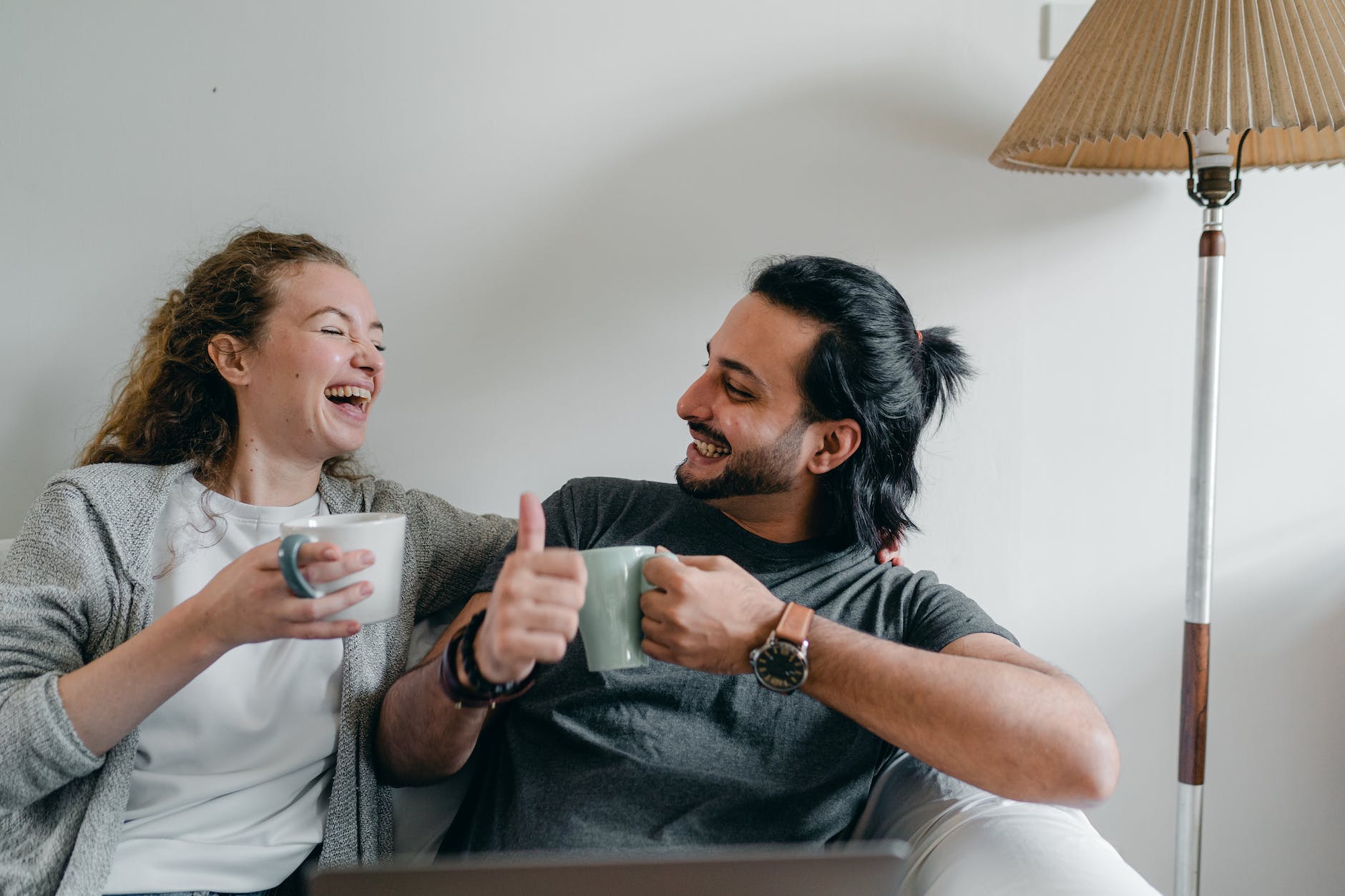 happy multiethnic couple drinking coffee and showing like gesture