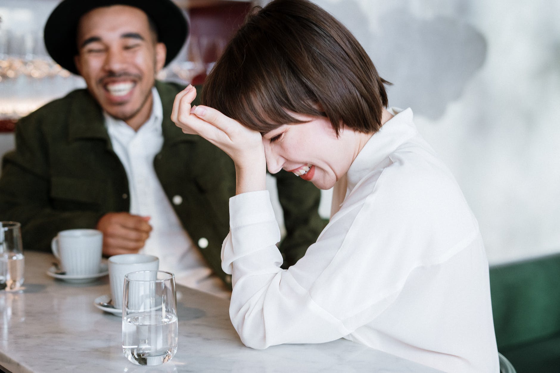 woman in white dress shirt holding clear drinking glass